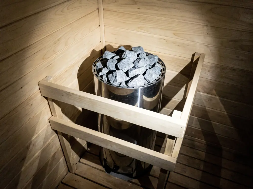Heater sauna dengan batu dan pagar kayu pengaman